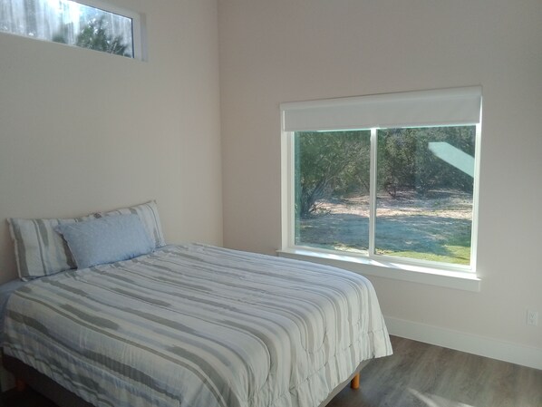 A bedroom with a bed, a window, and a view of a natural landscape. - NEW Casita, Located in upscale neighborhood on large lot. Private, safe, luxury. (Leander)