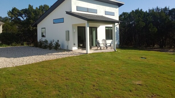 Una moderna casa a due piani con patio coperto e vialetto sterrato.