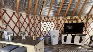 Um interior aconchegante com uma mesa de madeira, um banco e uma TV sobre um armário branco.