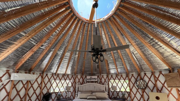 Um quarto aconchegante e circular com uma cama, um ventilador e uma placa de boas-vindas.