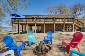 A building with a deck, outdoor seating with Adirondack chairs, and a fire pit. - Spacious Vacation Rental Home on Eufaula Lake! (Eufaula)