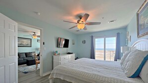 Ein Schlafzimmer mit Bett, Deckenventilator, Fernseher und Fenster mit Blick.