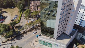 A GoInn Hotel with a modern glass facade, a parking lot, and surrounding greenery. - GO INN ARACRUZ (Aracruz)