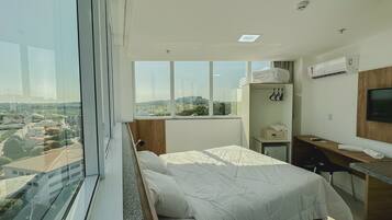 Una habitación de hotel moderna con una cama grande, un escritorio, un televisor y vistas a la ciudad.