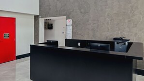 A reception desk with a black counter, a red door, and a wall with a textured pattern. - GO INN ARACRUZ (Aracruz)