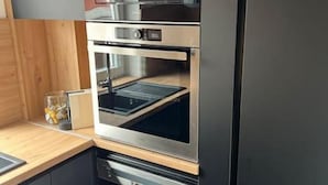 Kompakti keittiö, jossa on sisäänrakennettu uuni ja mikroaaltouuni, puinen työtaso ja mustat kaapit.