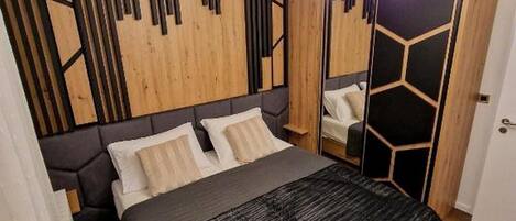 Une chambre moderne avec un lit, un miroir et un motif géométrique original sur le mur.