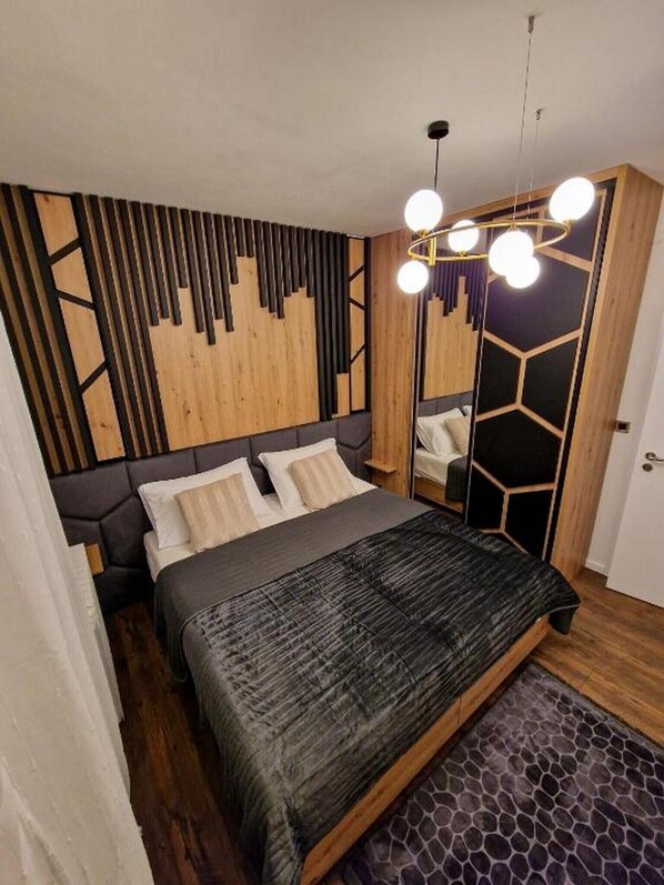 A modern bedroom with a bed, a mirror, and a unique geometric wall design.