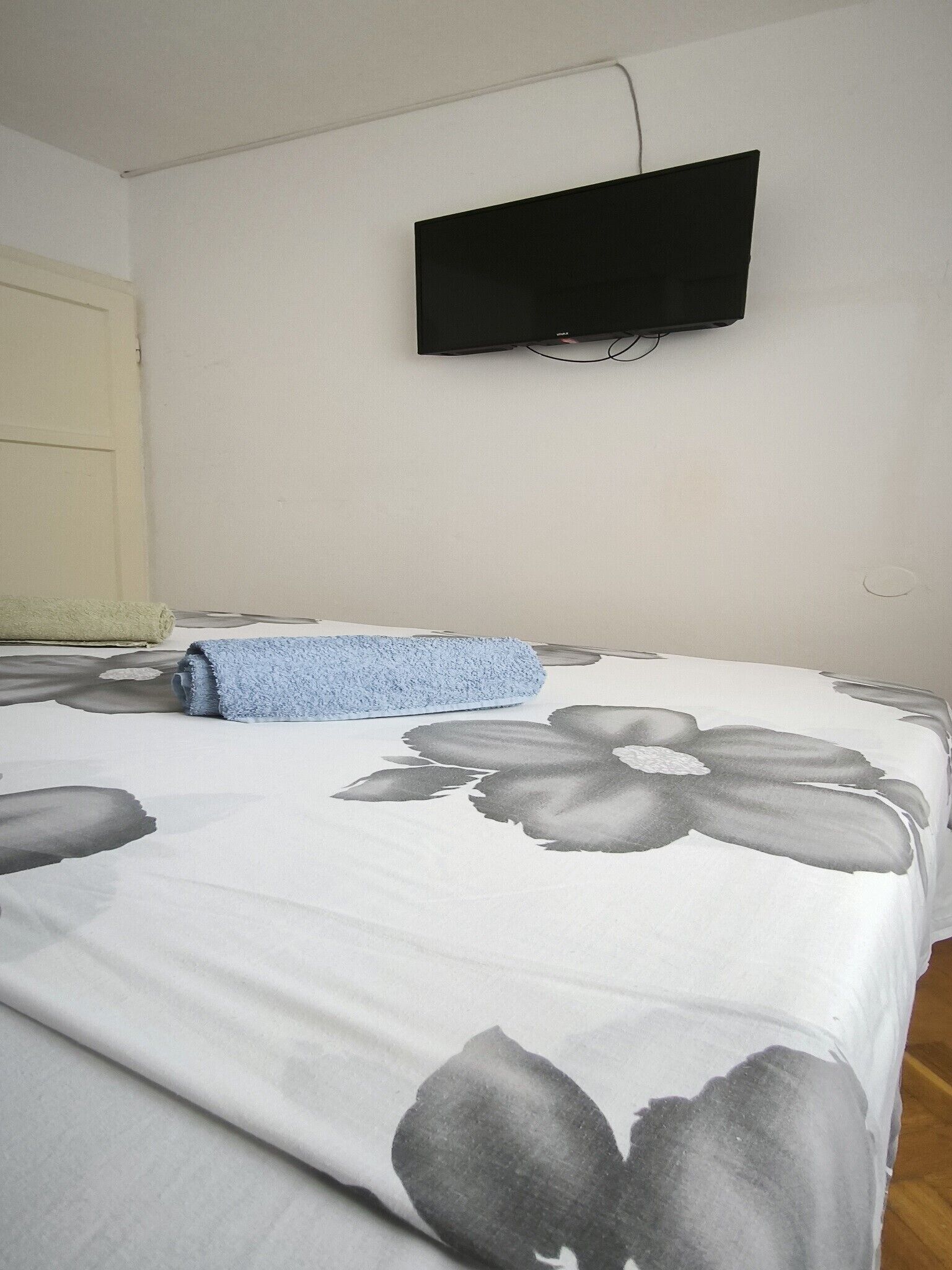 A bedroom with a bed, a television mounted on the wall, and a towel on the bed.