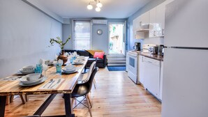 Cozinha compacta com área de refeições, um sofá e vista para a rua.