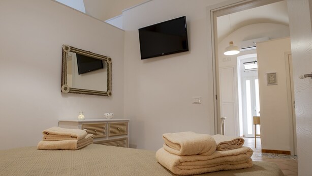 Un dormitorio con cama, televisor, espejo y cómoda.