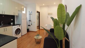 A compact living space with a kitchen, a dining area, and a large plant.