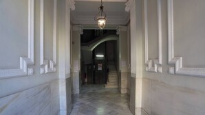 A marble-floored hallway with white decorative moldings and a hanging light fixture.