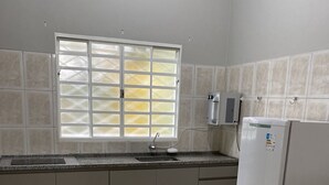 Una cucina con un piano di lavoro in granito, un lavello, una finestra con vetro satinato, un frigorifero e pareti rivestite di piastrelle.