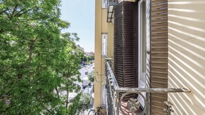 Näkymä parvekkeelta, jolta avautuu katu, jonka varrella on puita ja rakennuksia.
