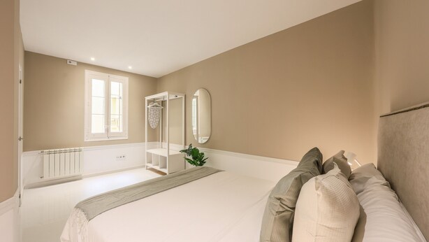 Une chambre avec un grand lit, un dressing, un miroir et un radiateur.