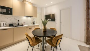 A modern kitchen with a marble countertop, a built-in oven, and a dining area with a round table and chairs. - Incredible design apartment 1ºCI (Madrid)