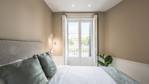 A bedroom with a large bed, a headboard, and a view of the outside through a door. - Incredible design apartment 1ºCI (Madrid)