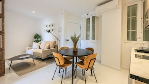 A modern living room with a round table and four chairs, a sofa, a coffee table, and a potted plant. - Incredible design apartment 1ºCI (Madrid)