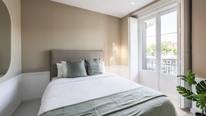 A bedroom with a large bed, a headboard, a potted plant, and a view of the outside through a sliding door. - Incredible design apartment 1ºCI (Madrid)