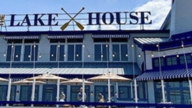 A building with a sign reading "LAKE HOUSE" and a waterfront view.