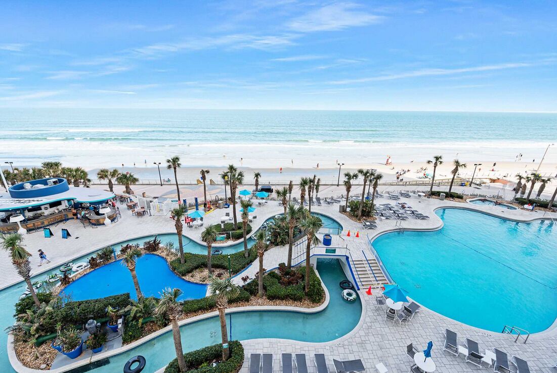 A resort with a large pool area, multiple swimming pools, and a beach view.