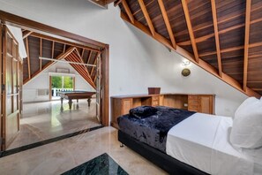 Ein Schlafzimmer mit Bett, Holz-Kopfteil und Blick auf einen Außenbereich.