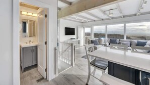 A modern kitchen with a white countertop, grey cabinets, and a wooden ceiling. - Unit 511: Cottage | Ocean View | Nautilus (Amagansett)