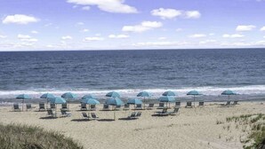 A beach with rows of lounge chairs and umbrellas, facing the ocean. - Unit 611: Two-Bedroom | 1st Floor-Dune View | Periwinkle (Amagansett)