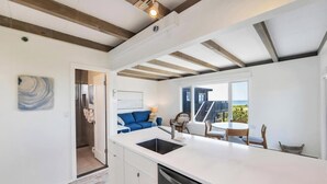 Una cocina moderna con una isla grande, un comedor con mesa y sillas, y vistas al exterior.