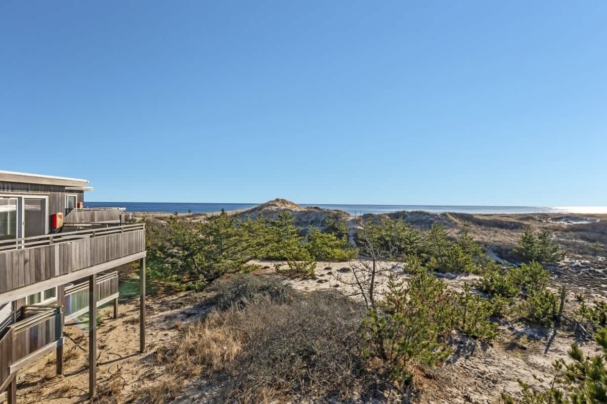 Une terrasse en bois offrant une vue sur la plage et les dunes.