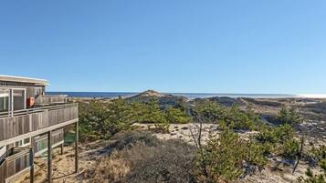 Une terrasse en bois offrant une vue sur la plage et les dunes.