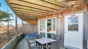 A covered outdoor area with a table and chairs, a door, and a window. - Unit 1011: Studio | 1st Floor-Garden View | Starfish (Amagansett)