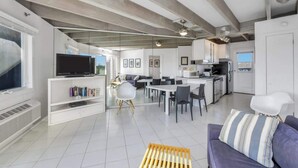 A modern living space with a kitchen, dining area, and entertainment area.
