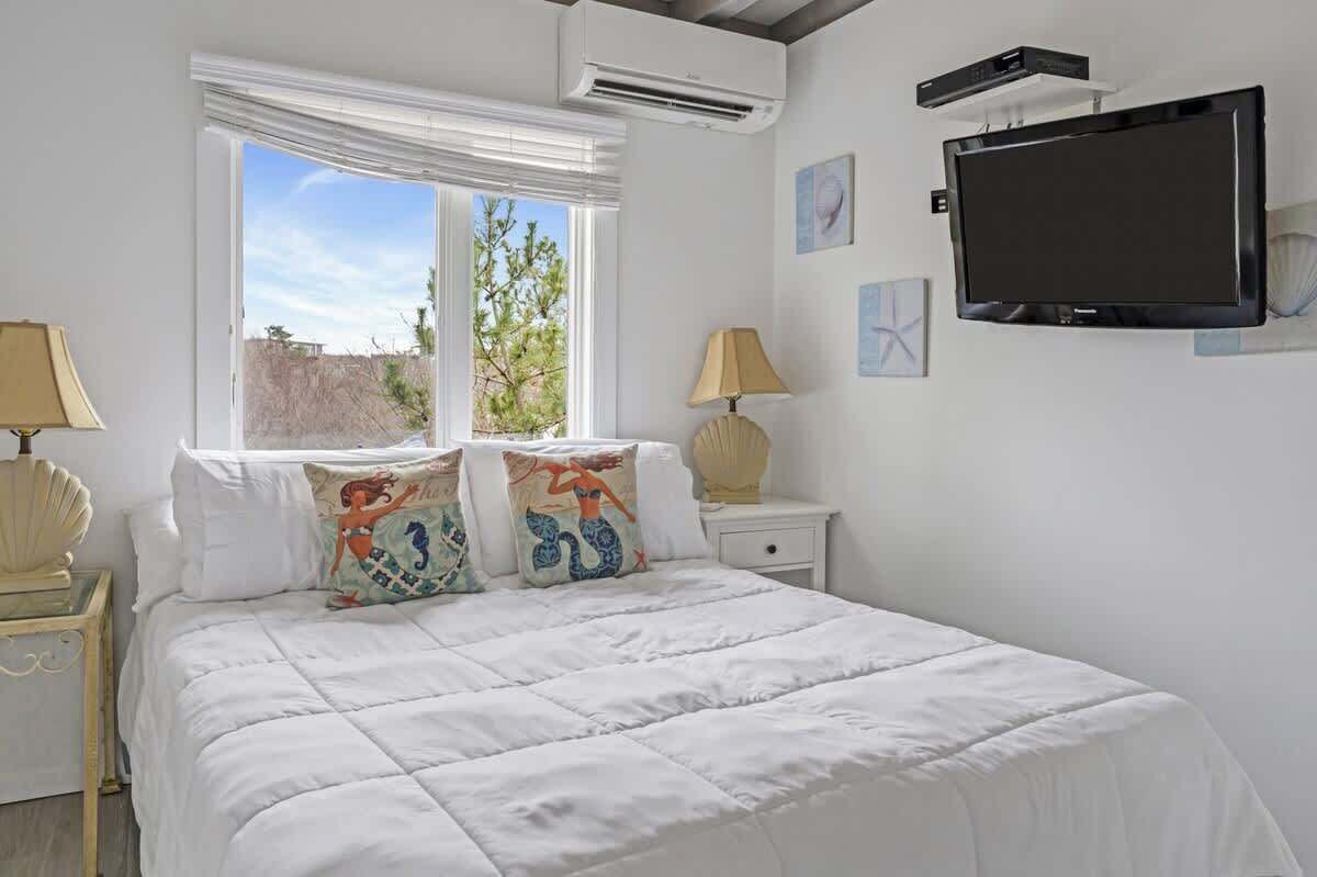 Une chambre à coucher avec un lit, une télévision et une fenêtre avec des rideaux.