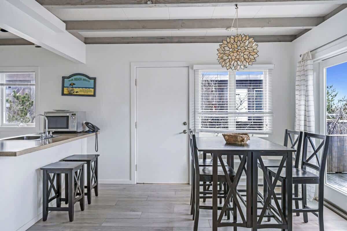 Una cocina moderna con microondas integrado, un lavamanos y un comedor con mesa y sillas.