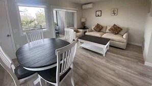 A living room with a round table, white chairs, a sofa, and a coffee table.