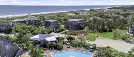 Un hotel frente a la playa con varias construcciones, una piscina y vistas al océano.