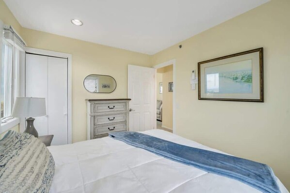 A bedroom with a bed, a dresser, a mirror, and a framed picture on the wall.