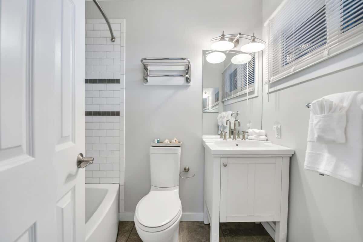 A bathroom with a white toilet, a sink with a mirror, and a towel rack.