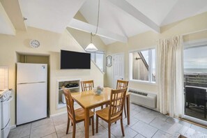 A compact kitchen with a dining table, chairs, a TV, and a view of the outside.