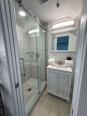 A modern bathroom with a glass shower enclosure, a vanity with a mirror, and a toilet.
