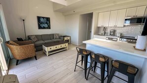 A modern kitchen with white cabinets, a central island, and bar stools. - Unit 1723: 1-Bedroom with Loft | 2nd Floor-Ocean Front Ocean View | Ocean Edge (Amagansett)