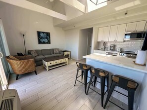 A modern kitchen with white cabinets, a central island, and bar stools.