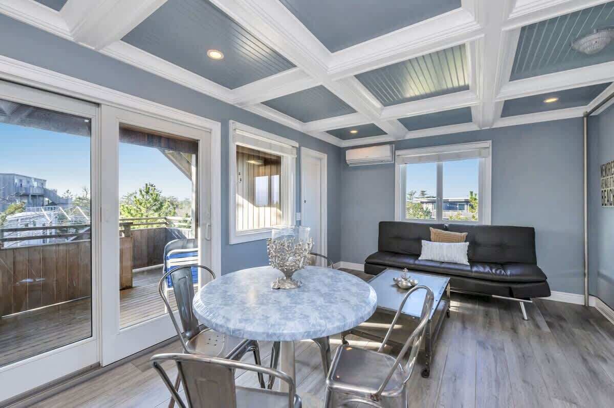Un balcón amplio con zona de comedor, un sofá de cuero negro y vista a un paisaje urbano.