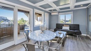 A spacious balcony with a dining area, a black leather sofa, and a view of a cityscape.
