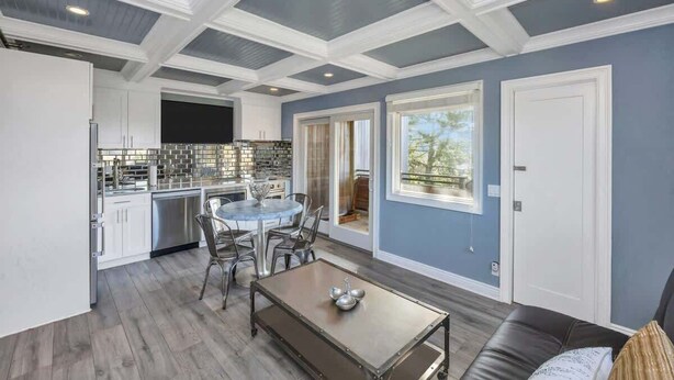 A modern kitchen with white cabinets, stainless steel appliances, and a dining area with a round table and chairs.