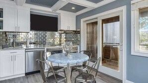 A modern kitchen with white cabinets, a stainless steel range hood, and a blue marble island with four chairs.