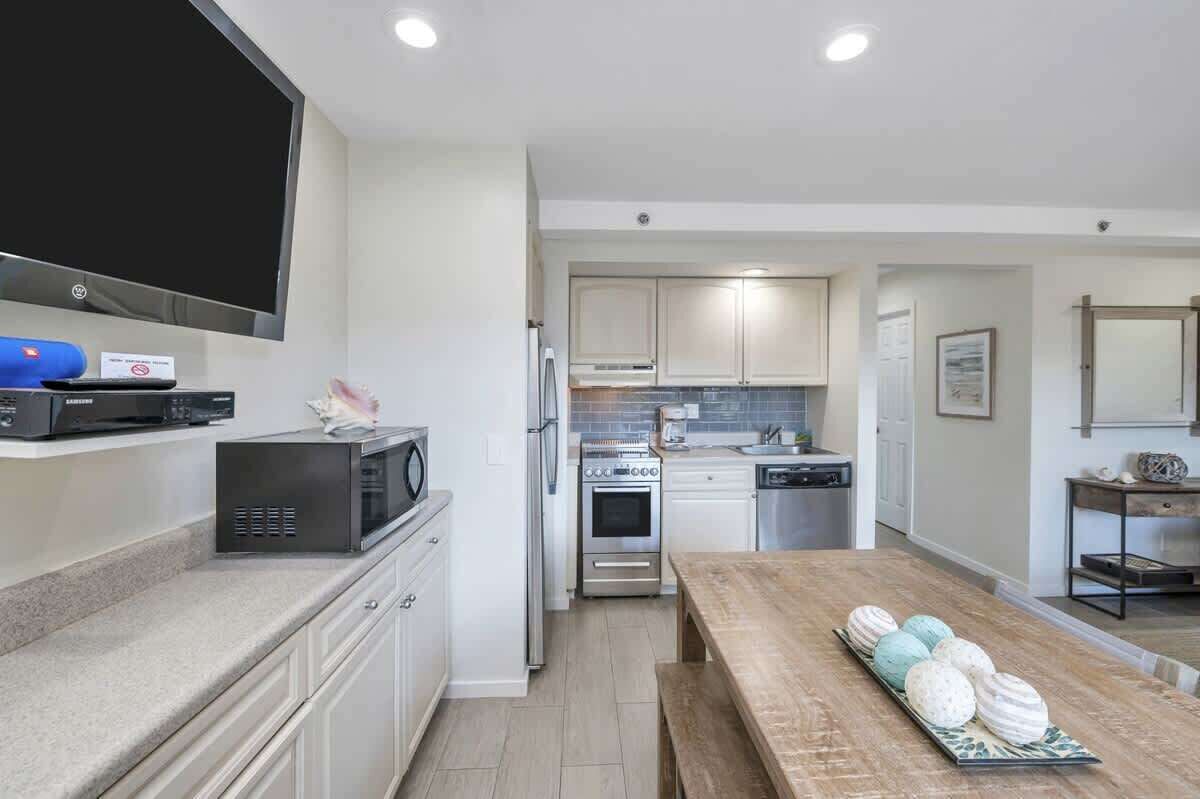 A modern kitchen with white cabinets, a microwave, a stove, and a dishwasher.