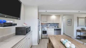 A modern kitchen with white cabinets, a microwave, a stove, and a dishwasher.